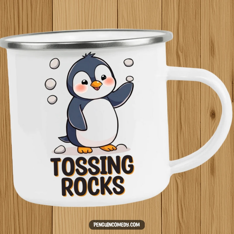 Funny penguin character hilariously juggling three tiny pebbles, ready for outdoor adventures on this durable enamel camping mug.