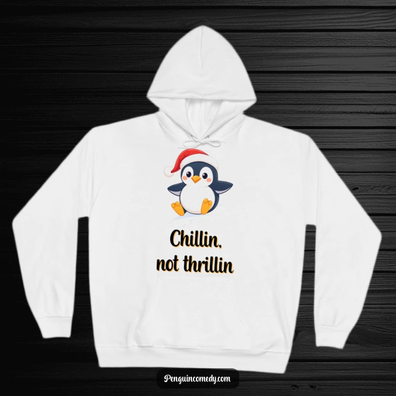 Funny and cozy hoodie featuring a happy penguin wearing a Santa hat, sliding downhill on a snowy winter day.