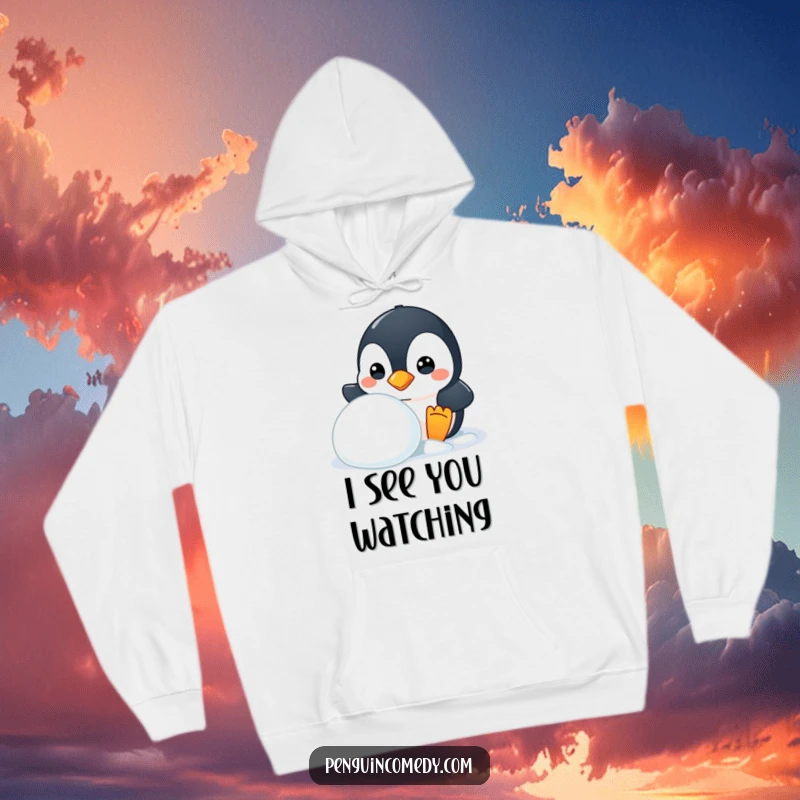 Funny hoodie with a mischievous penguin peeking from behind a snowball, cozy and humorous, a gift.